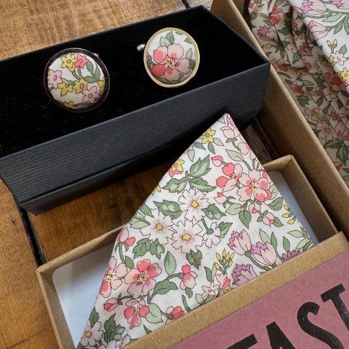 Floral cufflinks and pocket square set in a box on a wooden surface