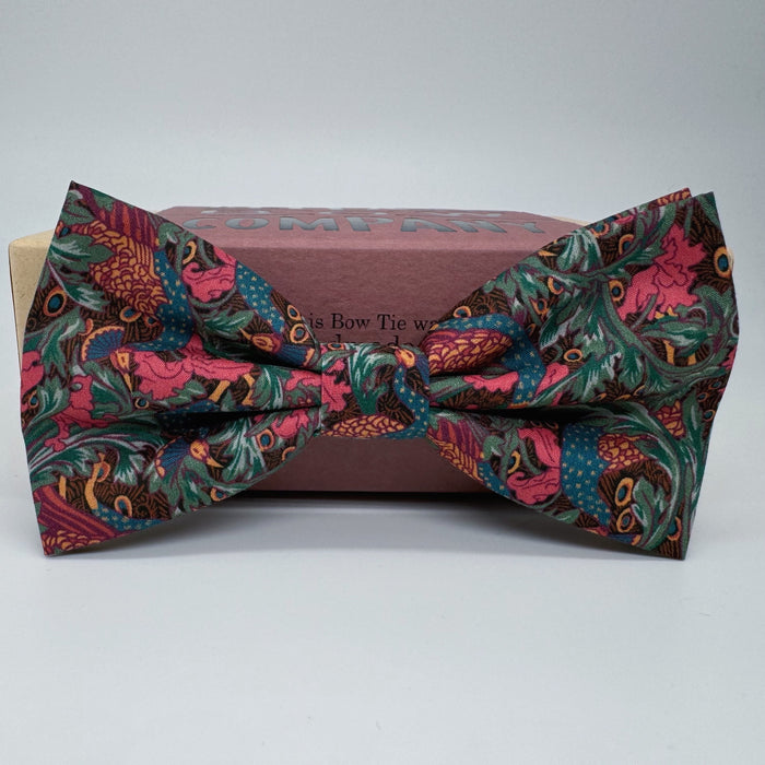 A bow tie with a peacock and floral pattern on a deep burgundy background by the belfast bow company